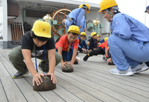 ヤシの実たわしで木甲板を磨く　「海王丸」で船員体験